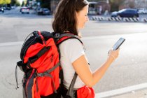 Молода жінка з червоним рюкзаком за допомогою смартфона в місті Верона (Італія). — стокове фото