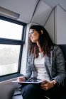 Brunette woman while traveling by train to work, with a tablet in her hands — Stock Photo