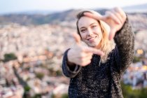 Portrait of young woman making a finger frame at sunrise above the city, Barcelona, Spain — Stock Photo