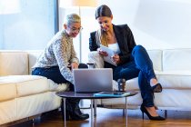 Two smiling businesswomen working together in lounge — Stock Photo