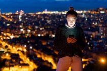 Young woman using cell phone at night above the city, Barcelona, Spain — Stock Photo