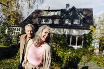 Felice coppia anziana in giardino della loro casa in autunno — Foto stock