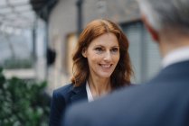 Portrait d'une femme d'affaires souriante parlant à un homme d'affaires en fonction — Photo de stock