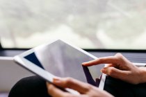 Woman's hand using a tablet while traveling by train — Stock Photo