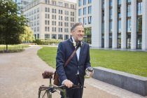 Homme d'affaires mature avec vélo dans la ville — Photo de stock