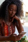 Ritratto di giovane donna africana in un caffè, controllando il suo smartphone — Foto stock
