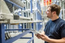 Worker using tablet in factory warehouse — Stock Photo