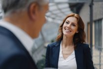 Portrait d'une femme d'affaires souriante parlant à un homme d'affaires en fonction — Photo de stock