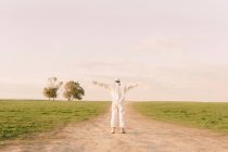 Rear view of man wearing protective suit standing on dirt track in the countryside — Stock Photo