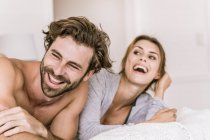 Laughing young couple lying in bed — Stock Photo