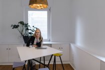 Porträt einer jungen Geschäftsfrau, die im Büro am Tisch sitzt — Stockfoto