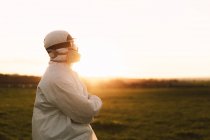 Man wearing protective suit and mask in the countryside at sunset — Stock Photo