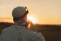 Rear viewof man wearing protective suit and mask in the countryside at sunset — Stock Photo