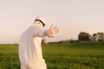 Rear view of man wearing protective suit in the countryside raising his hand — Stock Photo