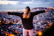 Jeune femme assise sur une rampe au-dessus de la ville en utilisant un téléphone portable, Barcelone, Espagne — Photo de stock