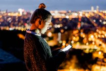 Jeune femme assise sur une rampe au-dessus de la ville en utilisant un téléphone portable, Barcelone, Espagne — Photo de stock