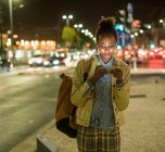 Portrait de jeune femme avec écouteurs et smartphone dans la ville la nuit, Lisbonne, Portugal — Photo de stock