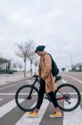 Молодий чоловік з велосипедом, що переходить вулицю в місті — стокове фото
