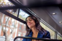 Молодая женщина слушает музыку в автобусе с наушниками, глаза закрыты — стоковое фото
