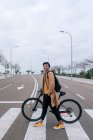Молодий чоловік з велосипедом, що переходить вулицю в місті — стокове фото