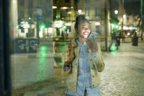 Portrait of young woman on the phone in the city by night, Lisbon, Portugal — Stock Photo