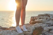 Gambe di giovane donna, in piedi su una scogliera in riva al mare — Foto stock