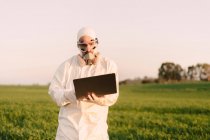 Man wearing protective suit and mask in the countryside using laptop — Stock Photo