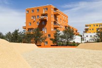 Germany, Bavaria, Munich, Sandy playground in front of orange painted residential building — Stock Photo