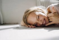 Портрет счастливой блондинки, лежащей на полу — стоковое фото