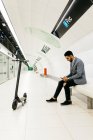 Jovem empresário com scooter elétrico e telefone celular esperando na estação de metrô — Fotografia de Stock