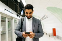Junger Geschäftsmann benutzt Handy in U-Bahn-Station — Stockfoto