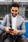 Jovem empresário sorridente com telefone celular e fones de ouvido no metrô — Fotografia de Stock