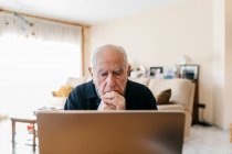 Retrato de homem sênior usando laptop em casa — Fotografia de Stock