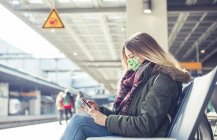 Молодая женщина в маске на платформе станции — стоковое фото