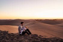 Vater sitzt mit Tochter in Sanddünen bei Sonnenuntergang, Gran Canaria, Spanien — Stockfoto