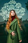 Портрет рудої молодої жінки, одягненої в модне зелене пальто, дивлячись вгору — стокове фото