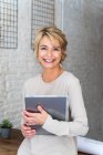 Portrait de femme mûre souriante dans le bureau tenant tablette graphique — Photo de stock