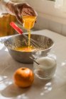 Рука жінки, що поливає апельсиновий сік у миску — стокове фото