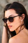 Jovem mulher usando óculos de sol na praia — Fotografia de Stock