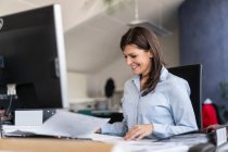 Smiling businesswoman working at desk in office — Stock Photo