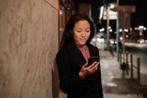 Jovem mulher usando smartphone na cidade à noite, Frankfurt, Alemanha — Fotografia de Stock