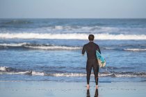 Handicapped surfer with surfboard at beach — Stock Photo