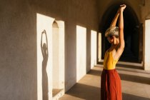 Retrato de adolescente loira com braços levantados olhando em sua sombra na parede — Fotografia de Stock