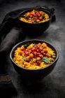 Studio shot di due ciotole di curry vegano con lenticchie rosse, patate dolci, spinaci, ceci arrosto di curcuma, semi di melograno e coriandolo — Foto stock