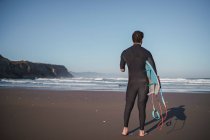 Rear view of handicapped surfer with surfboard at beach — Stock Photo