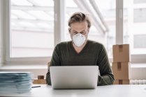 Businessman wearing protective mask and using laptop — Stock Photo