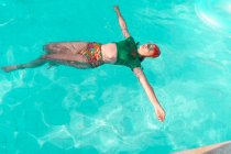 Mujer flotando en el agua en la piscina - foto de stock
