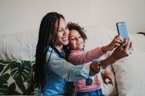 Felice madre e la sua figlioletta scattare selfie con smartphone a casa — Foto stock