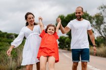 Happy parents lifting up daughter at countryside — Stock Photo
