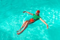 Mujer con neumático flotante y sandía en piscina - foto de stock